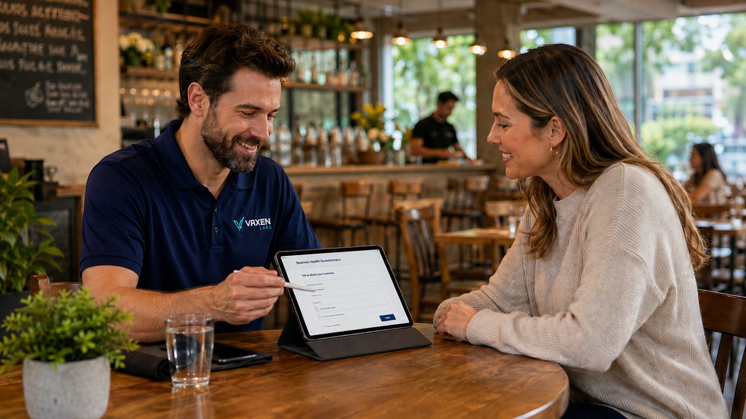 A Vaxen Labs team member reviewing a workflow on a tablet with a local business owner at a restaurant